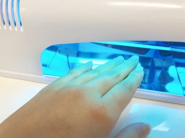 LEDライトでジェルを硬化させる女性の手元