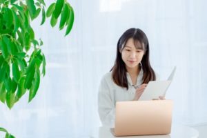 パソコンを見てメモを取る女性